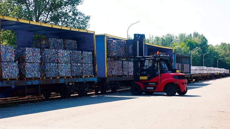 bales of cans being loaded onto trucks