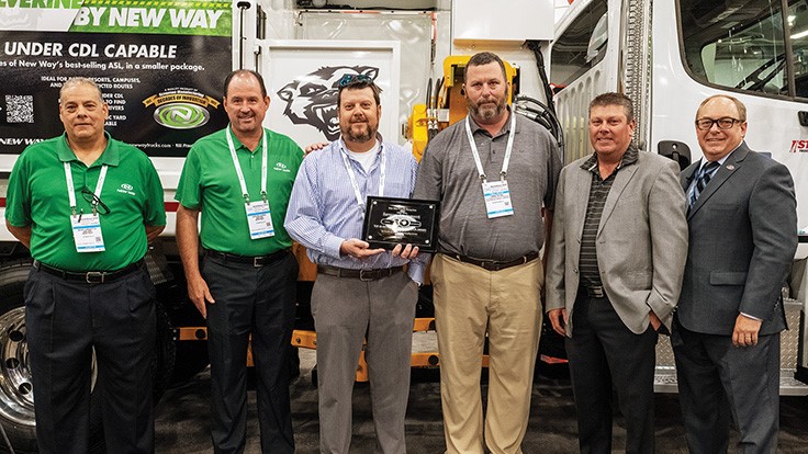 Top sales officials from Sansom Equipment and New Way Trucks with New Way CEO Mike McLaughlin post in front of a truck at WasteExpo.