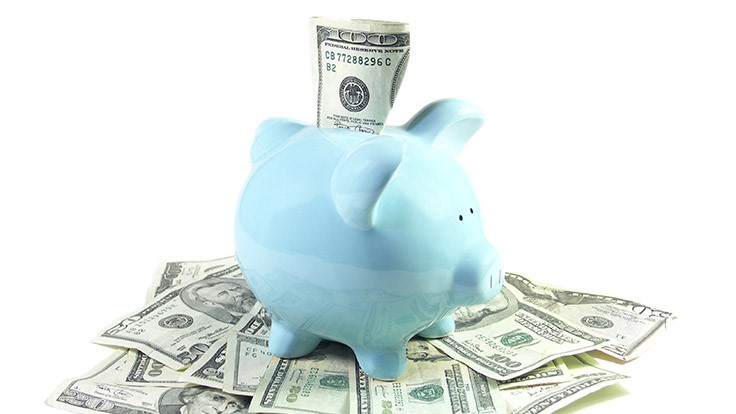 blue piggy bank on a pile of dollar bills
