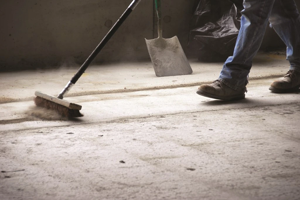 worker uses broom to sweep dust