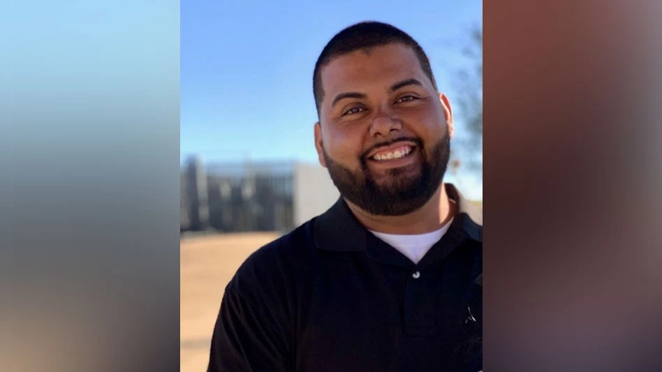 a smiling man with a beard wearing a blue polo