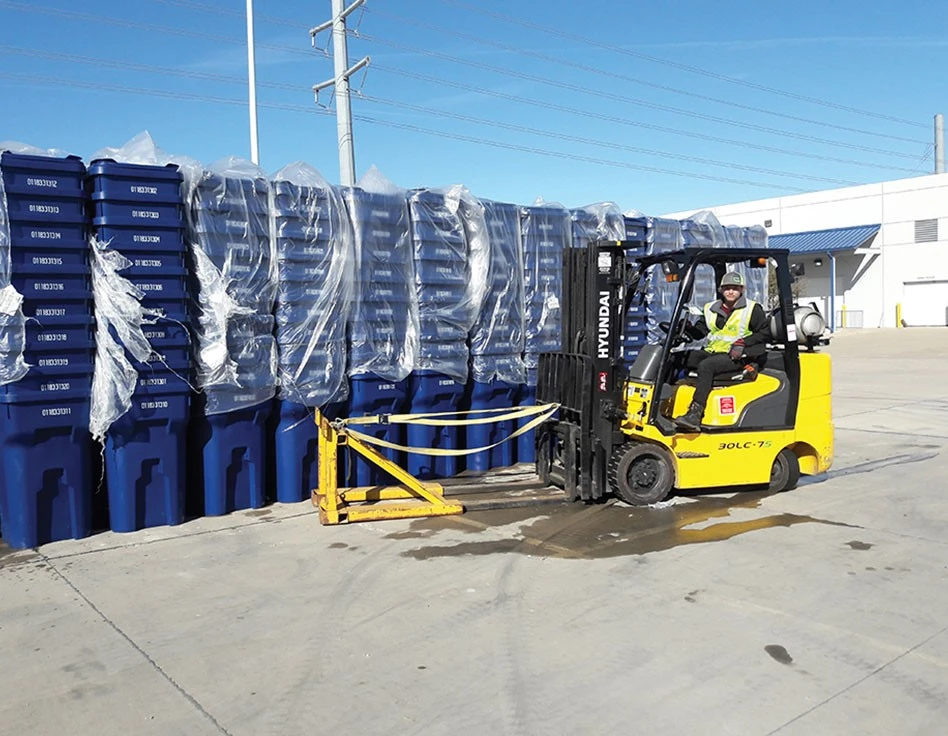 forklift with beside stacks of recycling carts