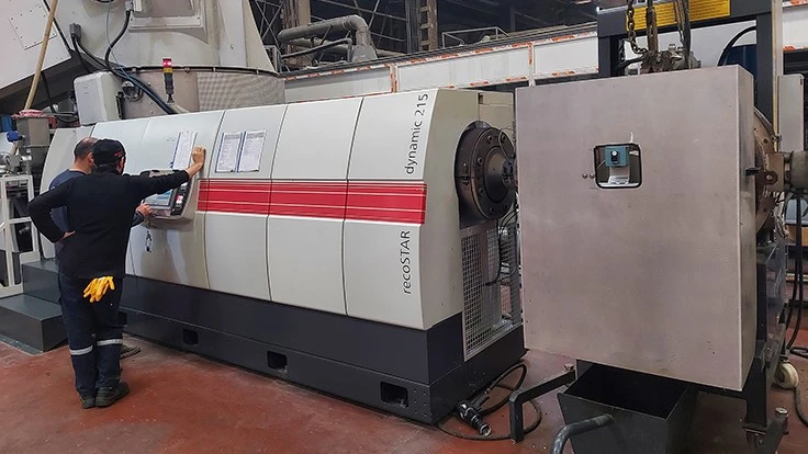 two men lean against starlinger machine