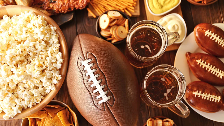 Football surrounded by Super Bowl snacks