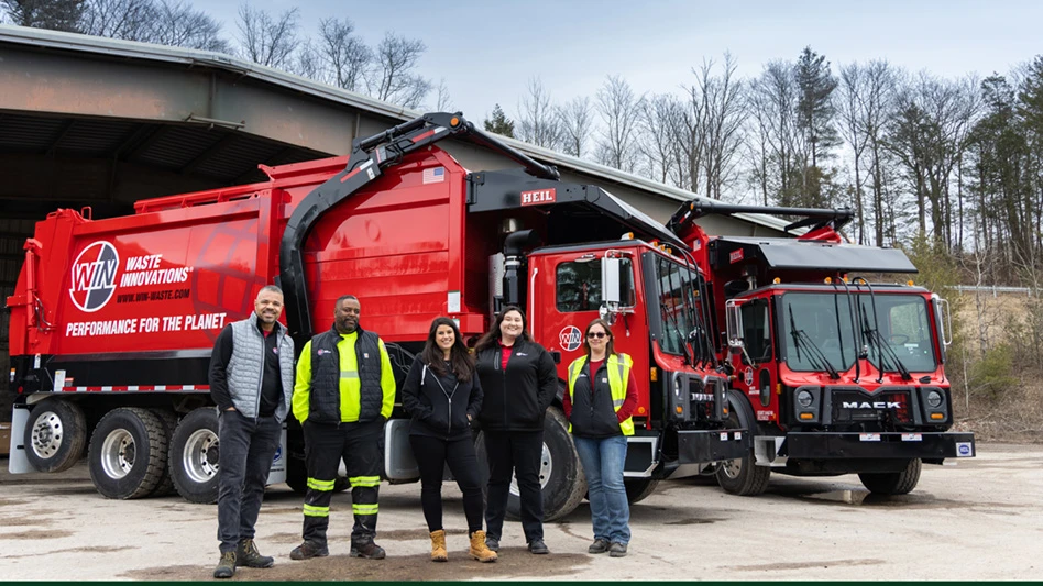 Five WIN Waste employees in front of two trucks