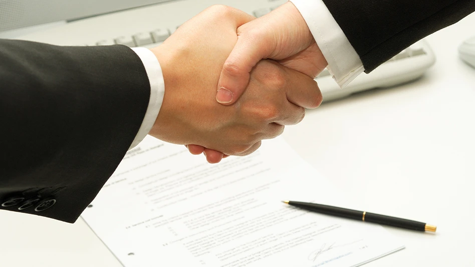 Close-up of a handshake between two men in suits, with a signed contract underneath them.