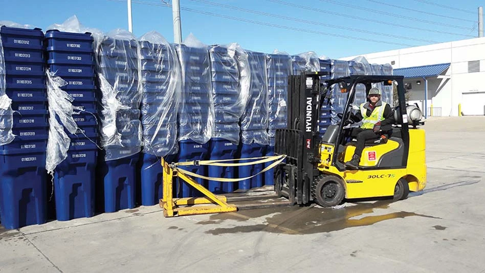 a yellow forklift in front of stacks of recycling carts