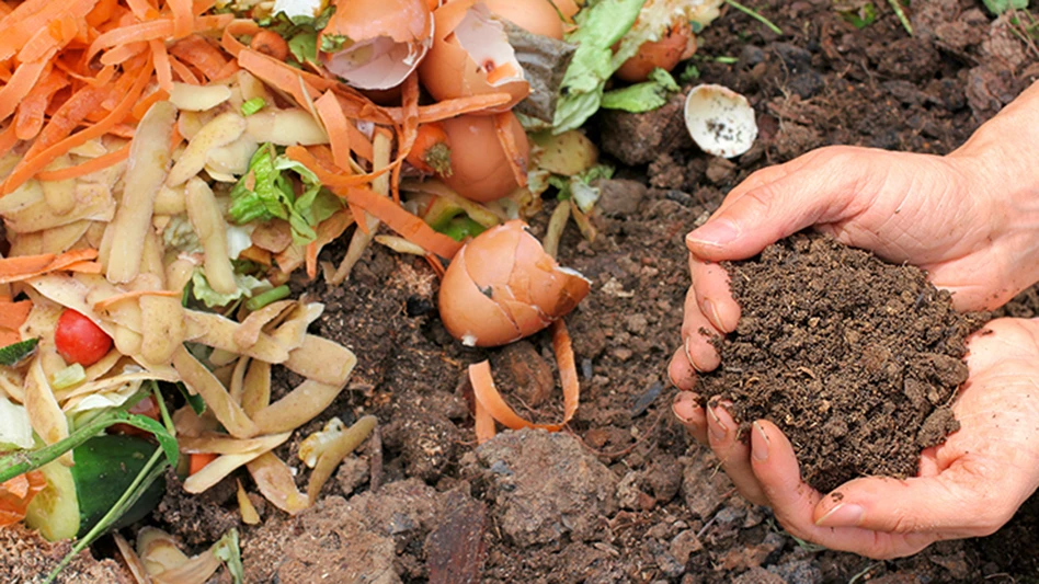 hands hold finished compost next to pile of food waste