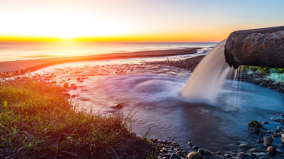 waste water spills from a pipe near the ocean