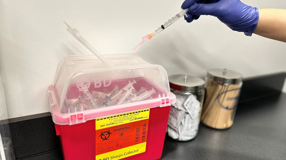 person placing syringe in medical sharps container