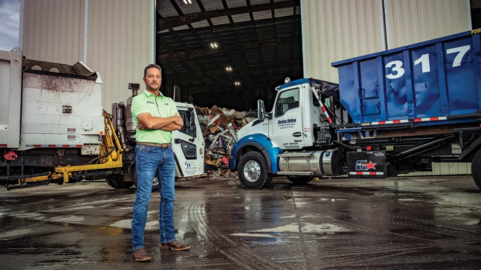 Superior Waste USA CEO Billy Dietrich in front of two trucks