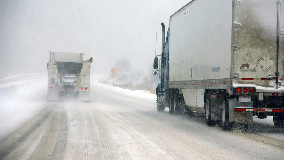 freight trucks driving in snowy conditions on highway