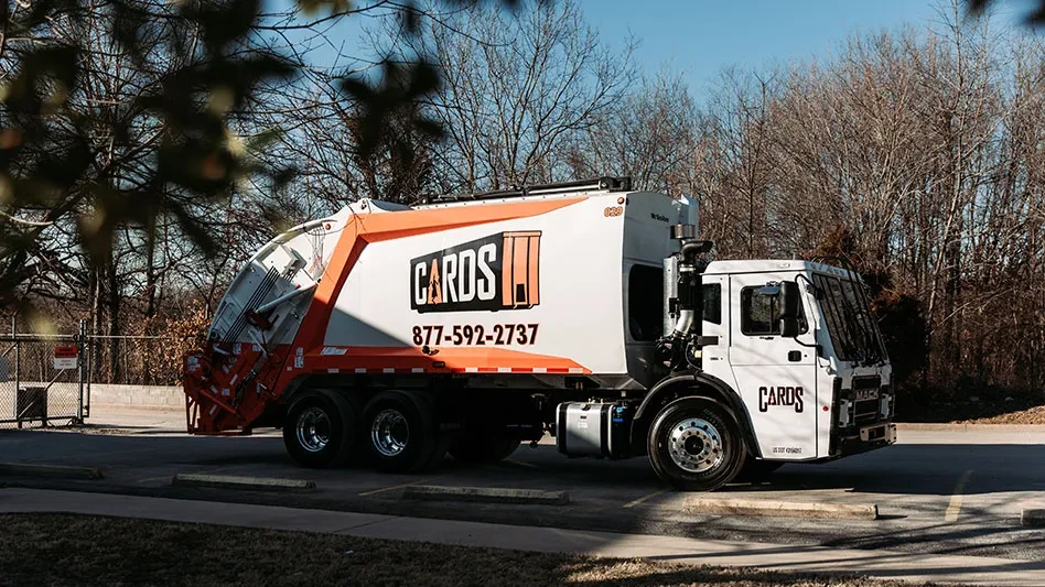 white and orange collection truck with a logo that says: CARDS