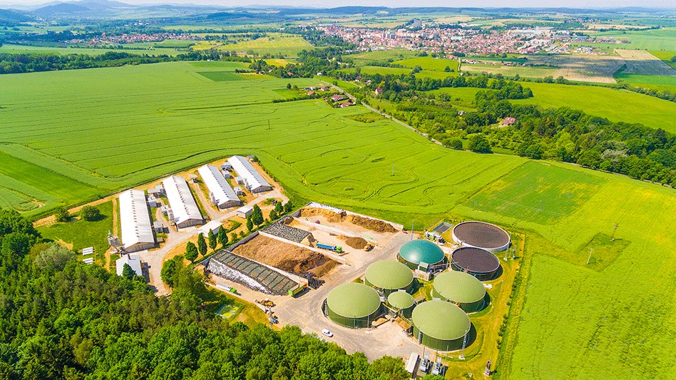 Aerial view over biogas plant and farm in green fields