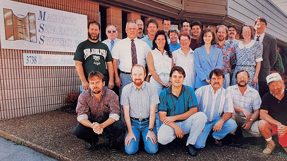 Photo of a group of employees posing in front of headquarters.