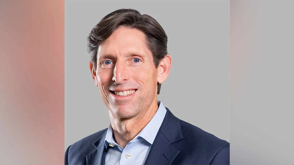 a smiling man with dark hair wearing a blue dress shirt and jacket