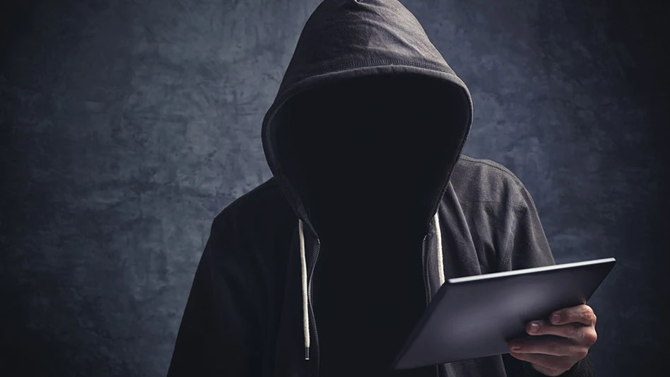 a man whose face is obscured wears a black hoodie and holds a tablet in front of a black background