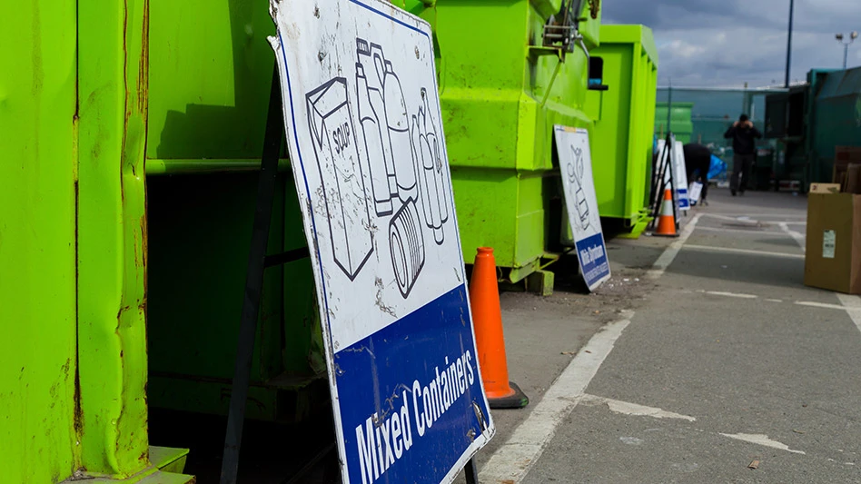 green dumpster with mixed containers sign in front