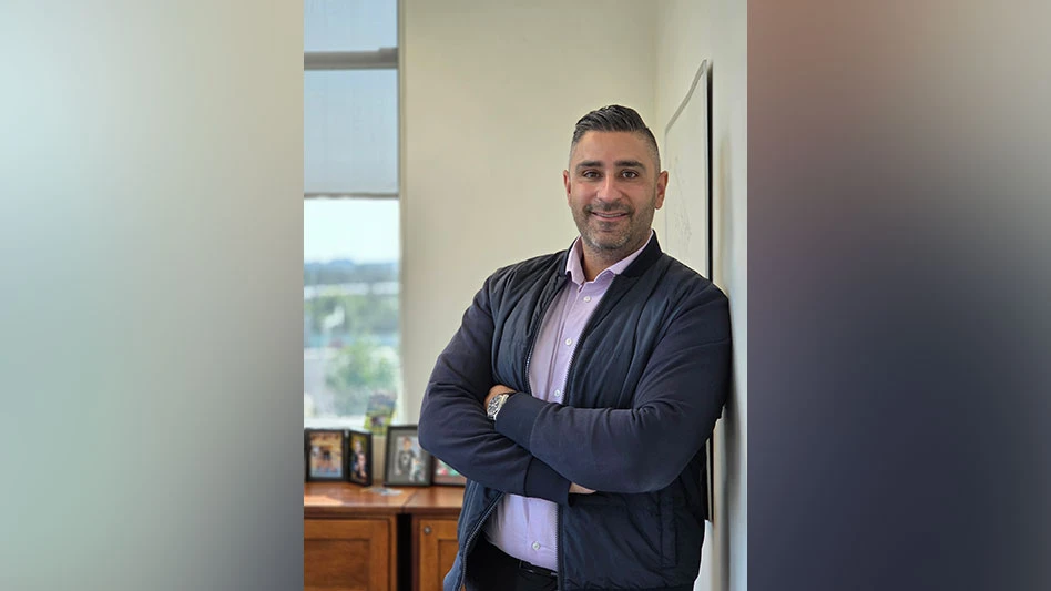 Man with brown skin and black hair, smiling, arms crossed