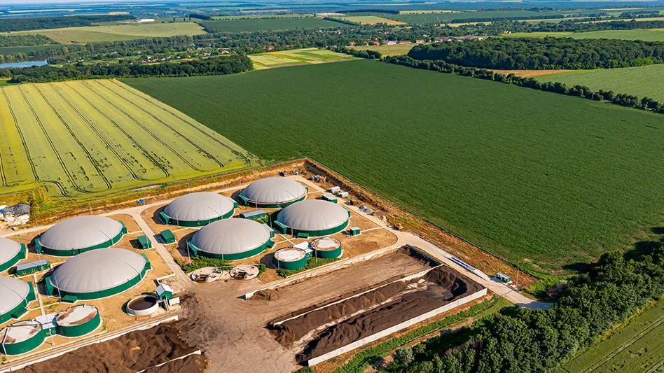 biogas plant in lower left corner of frame, surrounded by green fields