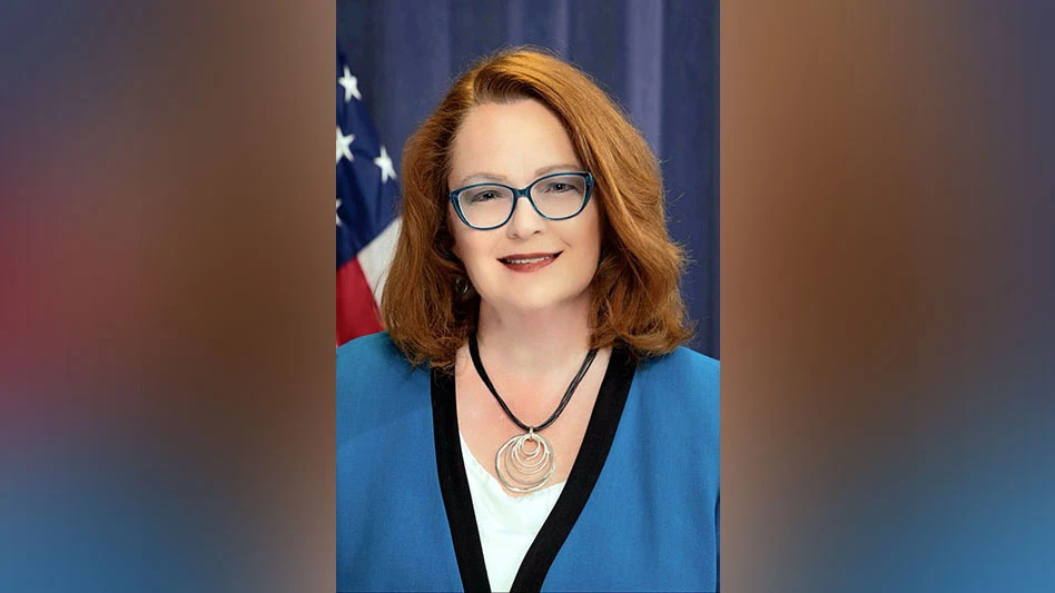 a smiling woman with red hair and glasses in a blue sweater