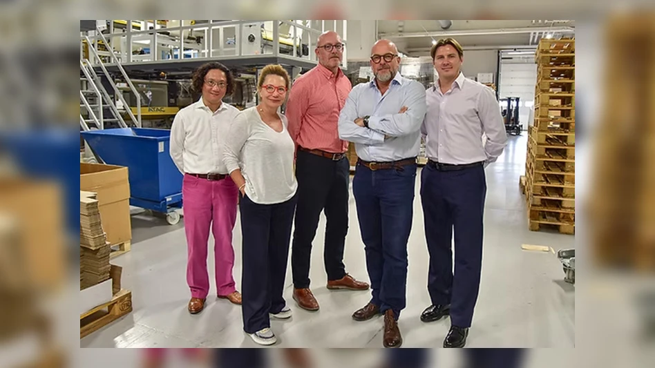 five people posing in manufacturing facility