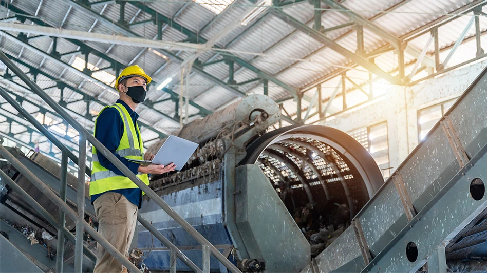 Adobe stock photo of a man in a construction vest at a waste management facility.