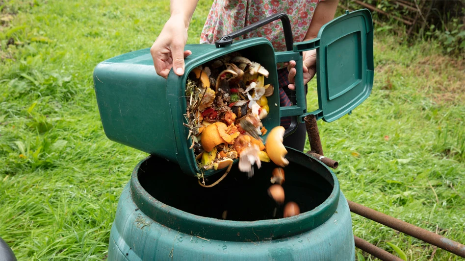 person pours materials into green compost bin