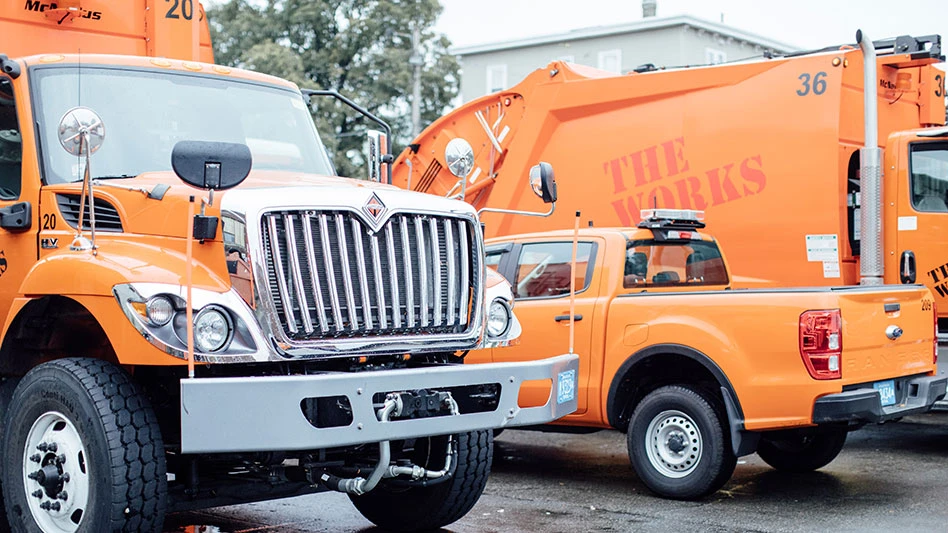 fleet of orange vehicles with "the works" printed on them