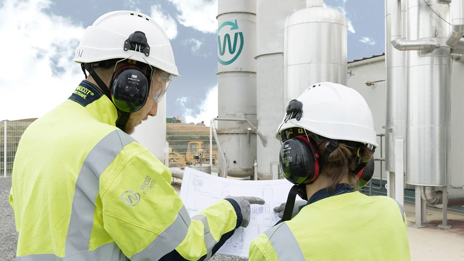 two people in hard hats and high-vis vests looking at schematics