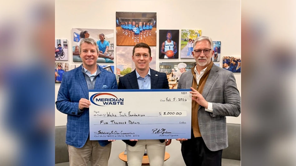 three people stand holding large check