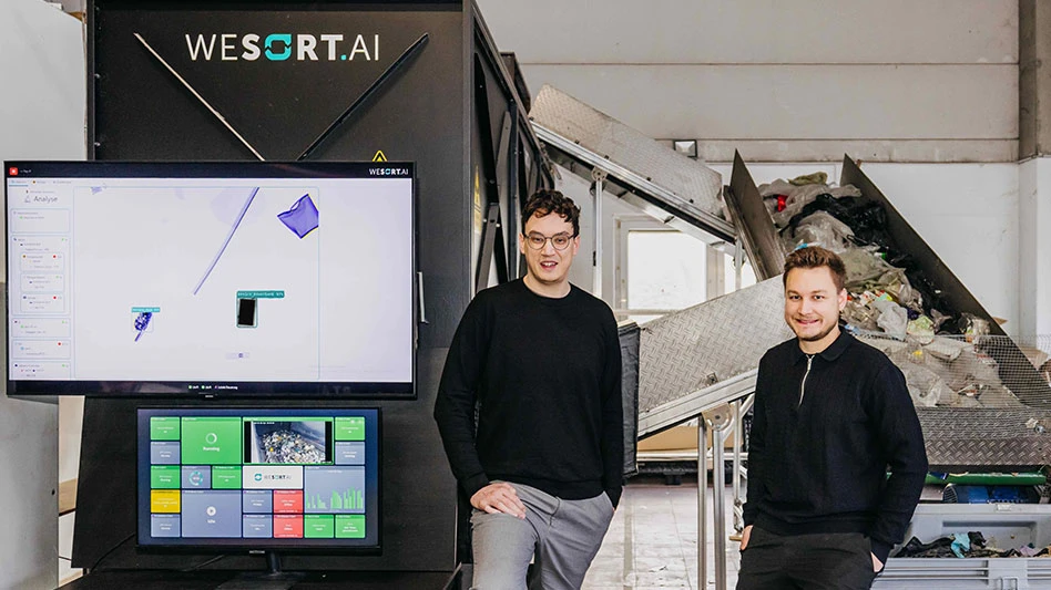 two men stand next to a sorting machine